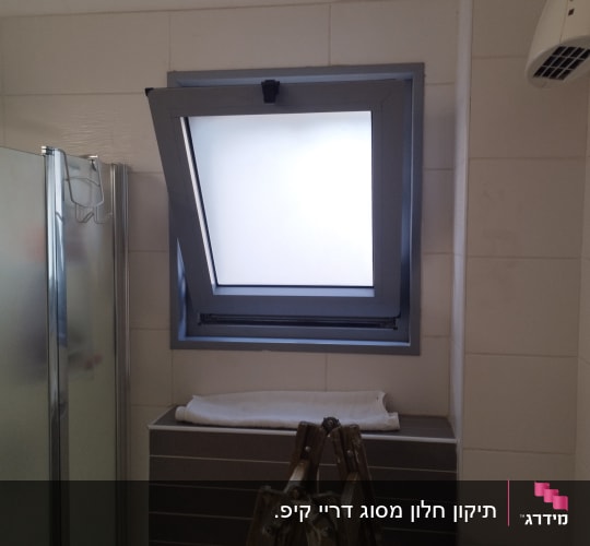 חלון עם תריס פתוח למחצה בחדר אמבטיה